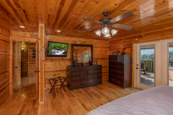 Dresser, mirror, TV, and deck access in a bedroom at Majestic Views, a 3 bedroom cabin rental located in Pigeon Forge