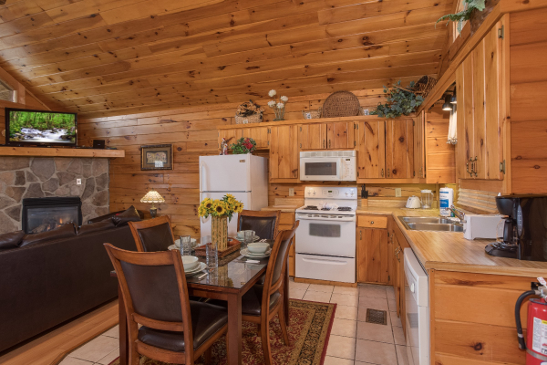 Dining space for four and kitchen with white appliances at Precious View, a 1 bedroom cabin rental located in Gatlinburg