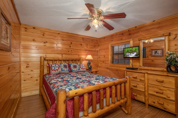 Bedroom with log bed, night stand, lamp, TV, and dresser at Pine Splendor, a 5 bedroom cabin rental located in Pigeon Forge