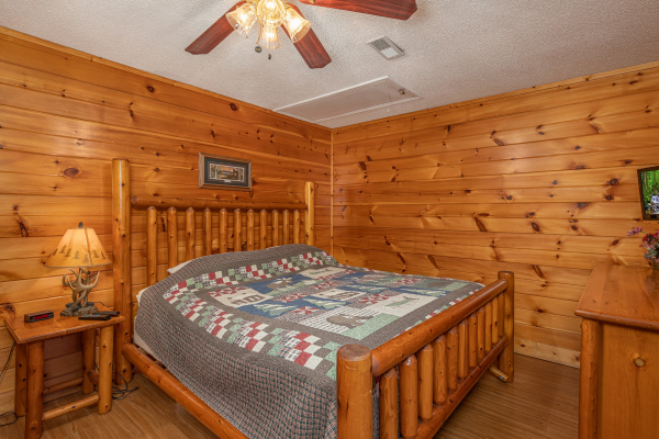 Bedroom with a bed, night stand, lamp, dresser, and TV at Pine Splendor, a 5 bedroom cabin rental located in Pigeon Forge