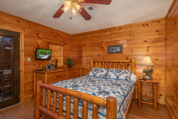 Log bed, dresser, TV, and nightstand in a bedroom at Pine Splendor, a 5 bedroom cabin rental located in Pigeon Forge