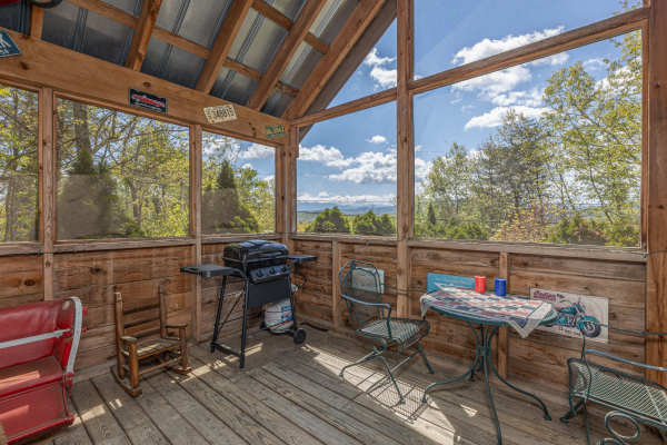 Grill and a table on the screened in porch at Rock Around the Clock, a 1 bedroom cabin rental located in Pigeon Forge