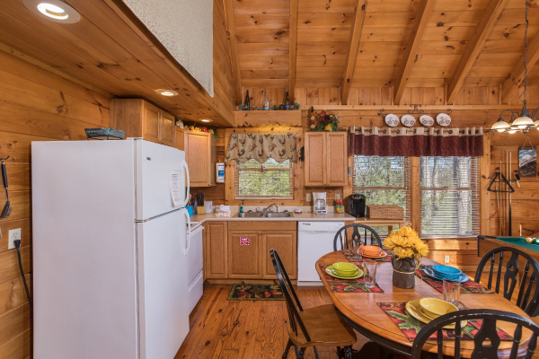 Kitchen with white appliances and a dining table for four at Cloud 9, a 1-bedroom cabin rental located in Pigeon Forge