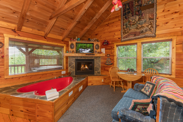 Fireplace, TV, and heart-shaped jacuzzi in the living room at Loving You, a 1 bedroom cabin rental located in Pigeon Forge