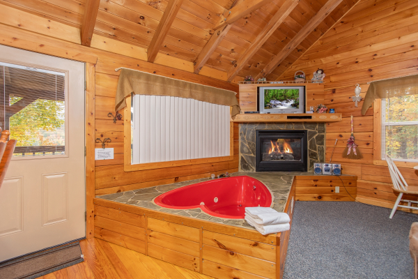 Heart shaped jacuzzi tub in front of a fireplace and television at Love Me Tender, a 1 bedroom cabin rental located in Pigeon Forge