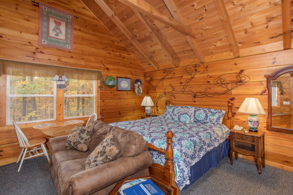 Loveseat and king bed on the main floor at Love Me Tender, a 1 bedroom cabin rental located in Pigeon Forge