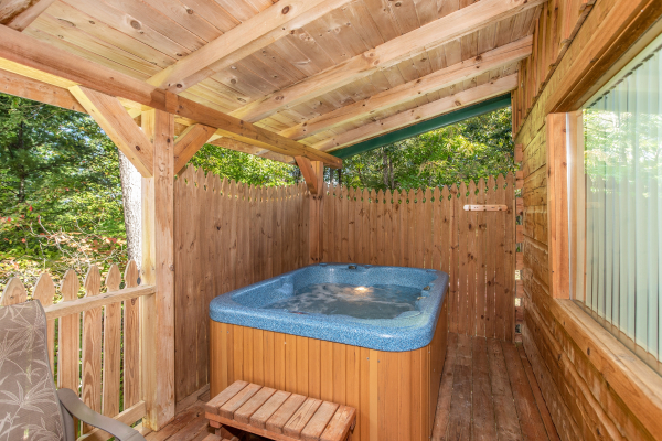 Hot tub with privacy fence on a covered deck at Forever Yours, a 1-bedroom cabin rental located in Pigeon Forge