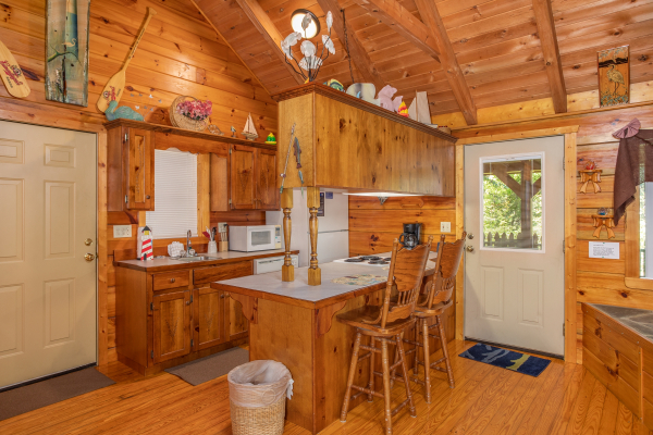 Kitchen with white appliances and counter top seating for two at at Forever Yours, a 1-bedroom cabin rental located in Pigeon Forge