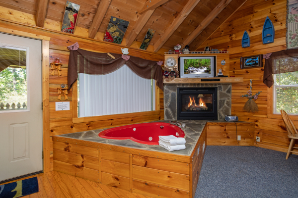 Studio living room with heart-shaped jacuzzi tub, fireplace, and TV at Forever Yours, a 1-bedroom cabin rental located in Pigeon Forge