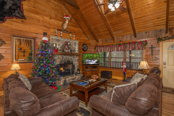 Living room with fireplace, TV, and Christmas decor at Pigeon Forge Pleasures, a 3 bedroom cabin rental located in Pigeon Forge