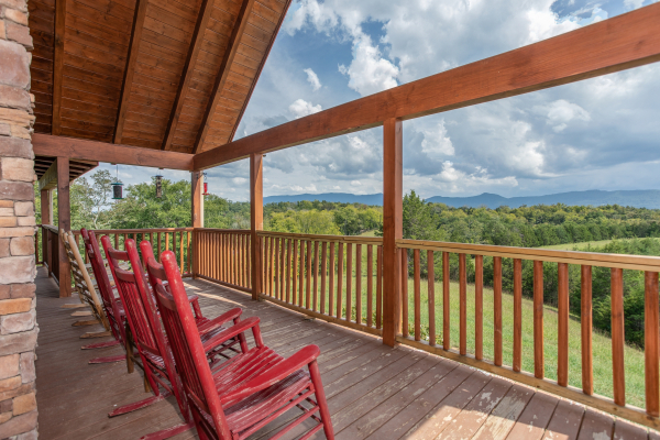 Rocking chairs lined up on a covered deck with lake and mountain views at Cedar Creeks, a 2-bedroom cabin rental located near Douglas Lake