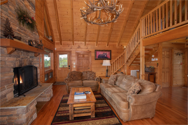 Couch, sofa, fireplace, and custom chandelier in the living room at Cedar Creeks, a 2-bedroom cabin rental located near Douglas Lake