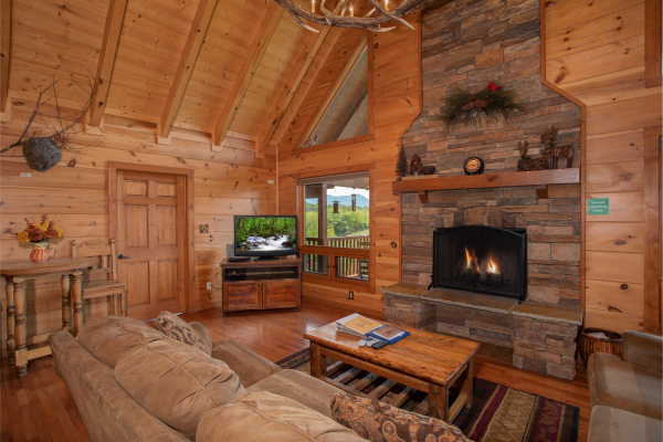 A vaulted living room with fireplace and television at Cedar Creeks, a 2-bedroom cabin rental located near Douglas Lake