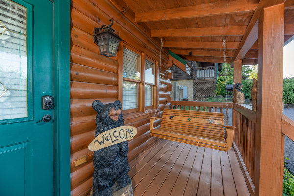 Swing and custom welcome sign on a covered front porch at Southern Charm, a 2 bedroom cabin rental located in Pigeon Forge