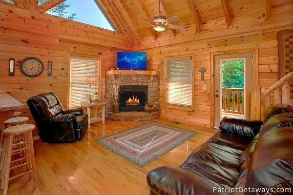 Living room with stone fireplace and leather seating at Alpine Sundance Trail, a 3 bedroom cabin rental located in Pigeon Forge