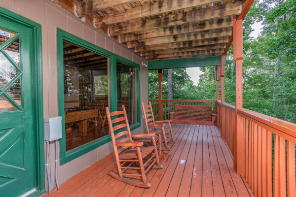 Deck with rocking chairs and a porch swing at Bushwood Lodge, a 3-bedroom cabin rental located in Gatlinburg