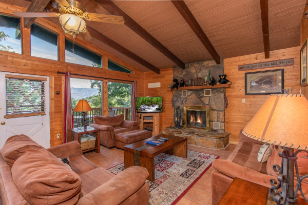 Living room with couch, loveseat, and chair, floor-to-ceiling windows, and a fireplace at Bushwood Lodge, a 3-bedroom cabin rental located in Gatlinburg