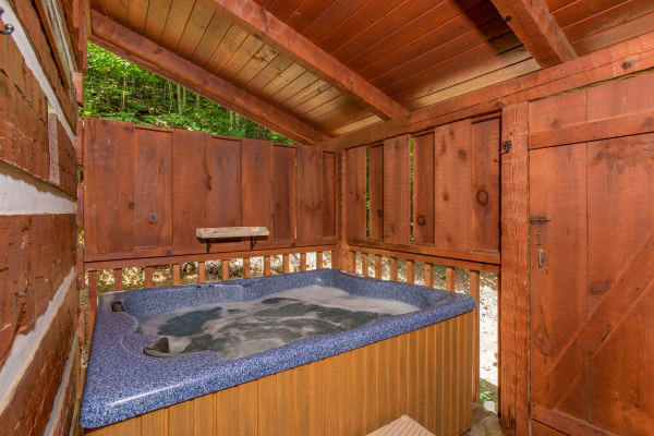 Hot tub on a covered deck with privacy fence at Bearfoot Crossing, a 1-bedroom cabin rental located in Pigeon Forge