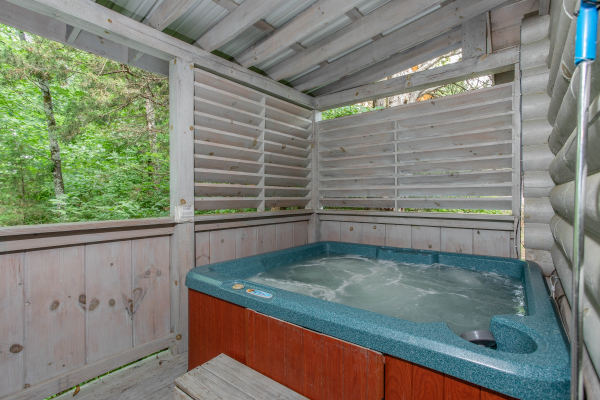 hot tub on a covered deck with privacy fence at alpine something blue a 1 bedroom cabin rental located in pigeon forge