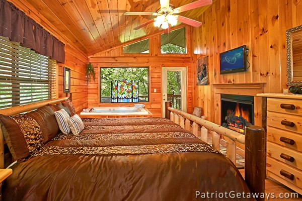 king sized log bed with fireplace and jacuzzi at always together forever a 1 bedroom cabin rental located in pigeon forge