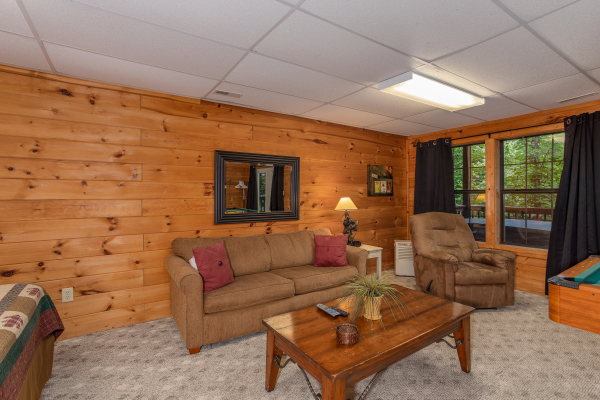Couch and coffee table in the game room at A View for You, a 1 bedroom cabin rental located in Pigeon Forge
