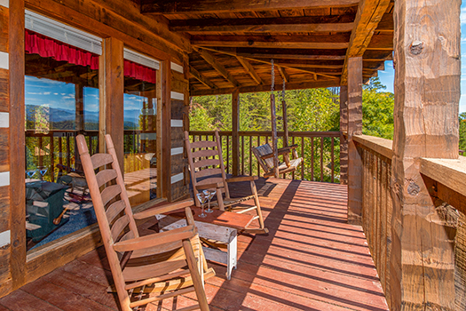 Rocking chairs and a porch swing on a covered deck at A Postcard View, a 1 bedroom cabin rental located in Pigeon Forge