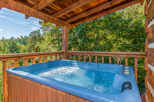 Hot tub on a covered porch with a woods view at A Postcard View, a 1 bedroom cabin rental located in Pigeon Forge