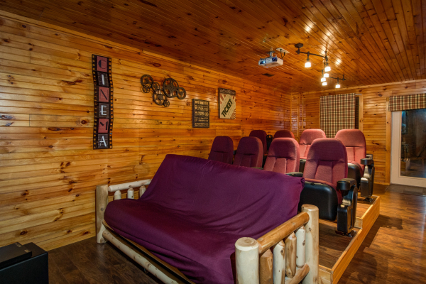 Movie seats and a futon in the theater room of cabin 1 at The Settlement, a 10 bedroom cabin rental located in Pigeon Forge