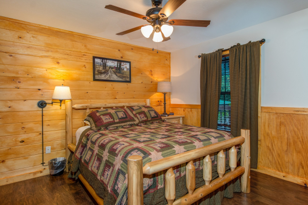 A bedroom with a log bed, night stands, and lamps in cabin 1 at The Settlement, a 10 bedroom cabin rental located in Pigeon Forge