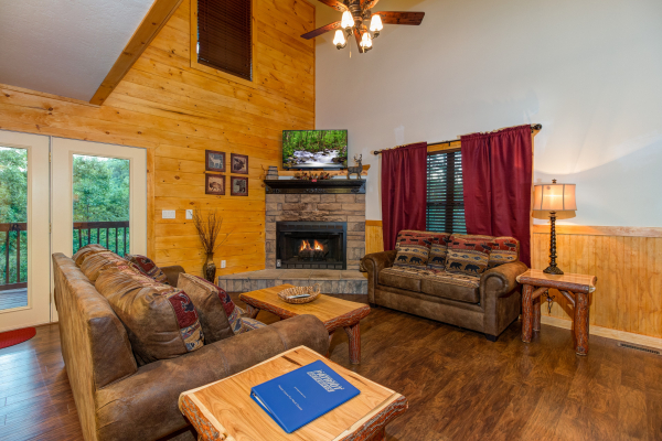 Living room with a fireplace and TV in cabin 1 at The Settlement, a 10 bedroom cabin rental located in Pigeon Forge
