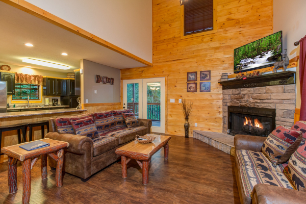 Sofa, fireplace, and TV in the living room of cabin 1 at The Settlement, a 10 bedroom cabin rental located in Pigeon Forge