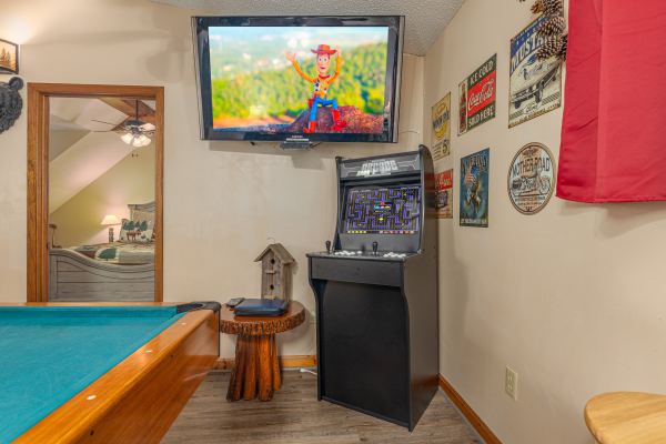 Pool table, arcade game, and tv in the game room at Magic Moments, a 2 bedroom cabin rental located in Pigeon Forge