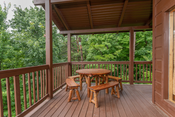 Dining space for four on the covered deck at Into the Mist, a 3 bedroom cabin rental located in Pigeon Forge