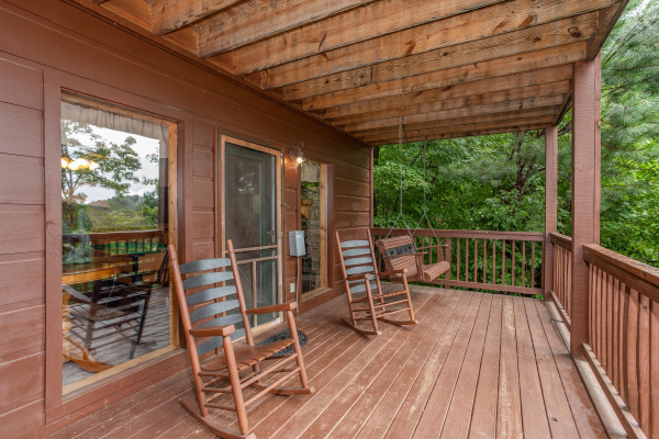 A porch swing and rocking chairs on a lower level deck at Into the Mist, a 3 bedroom cabin rental located in Pigeon Forge