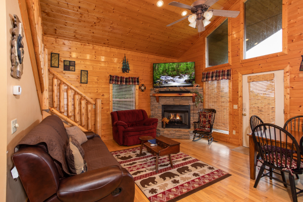 Living room with a fireplace, large TV, and dining space at Into the Mist, a 3 bedroom cabin rental located in Pigeon Forge