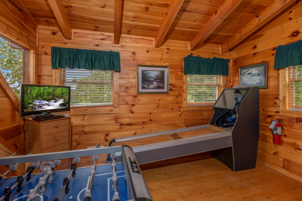 Skeeball, foosball, and a dresser with a TV at Hummingbird's Views, a 1 bedroom cabin rental located in Pigeon Forge