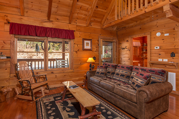 Sofa in the living room at Bear Hug Hideaway, a 1-bedroom cabin rental located in Pigeon Forge