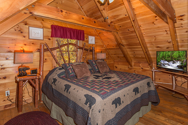 King bed, night stands and lamps, and TV in a bedroom at Bear Hug Hideaway, a 1-bedroom cabin rental located in Pigeon Forge