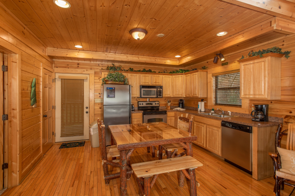 Dining table for six and kitchen with stainless appliances at Let the Good Times Roll, a 2 bedroom cabin rental located in Pigeon Forge