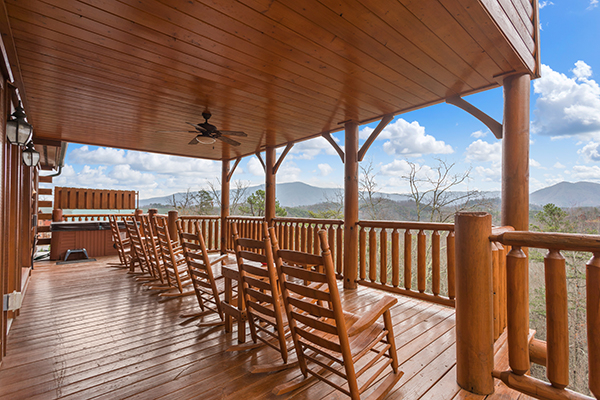 Rocking chairs lined up on a covered deck overlooking the mountains at Grand Timber Lodge, a 5-bedroom cabin rental located in Pigeon Forge
