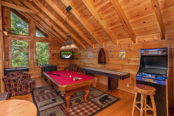 Red felted pool table, shuffleboard table, and arcade game at Bearfoot Paradise, a 3-bedroom cabin rental located in Pigeon Forge