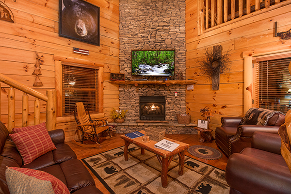 Living room with stacked stone fireplace and television at Bearfoot Paradise, a 3-bedroom cabin rental located in Pigeon Forge