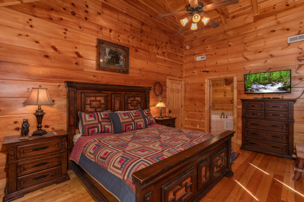 Bedroom with a king-sized bed, dresser, and television at Bearfoot Paradise, a 3-bedroom cabin rental located in Pigeon Forge