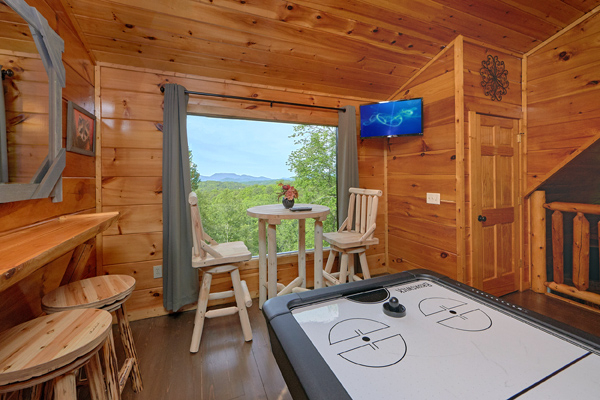 Bar top table for two, air hockey table, and TV in the game loft at Makin' Honey, a 1 bedroom cabin rental located in Pigeon Forge