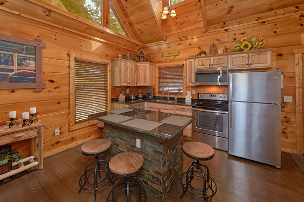 Kitchen with stainless appliances, granite counters, and bar seating for four at Makin' Honey, a 1 bedroom cabin rental located in Pigeon Forge
