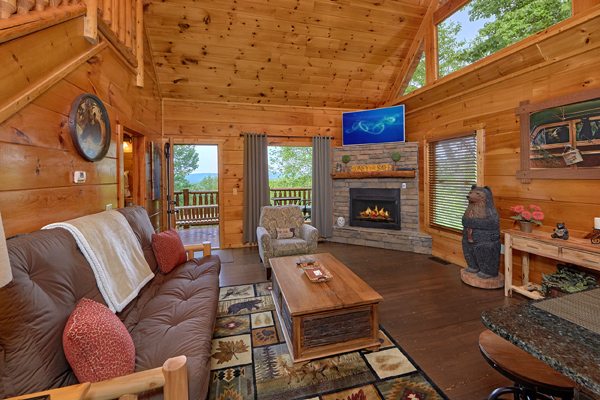 Living room with fireplace, TV, and deck access at Makin' Honey, a 1 bedroom cabin rental located in Pigeon Forge