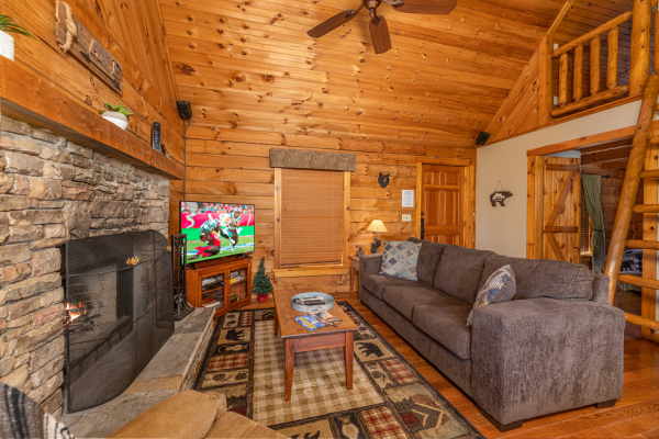 Sofa, fireplace, and TV in the living room at Golden Memories, a 1 bedroom cabin rental located in Pigeon Forge