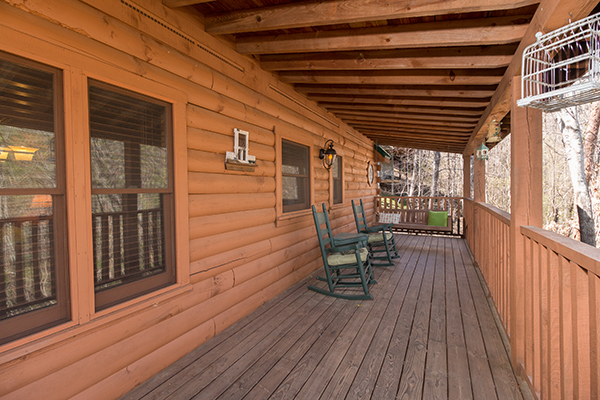 Covered deck with rocking chairs and a swing at Golden Memories, a 1-bedroom cabin rental located in Pigeon Forge