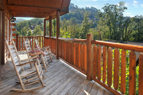 Covered deck with rocking chairs overlooking the woods at Kick Back & Relax! A 4 bedroom cabin rental located in Pigeon Forge