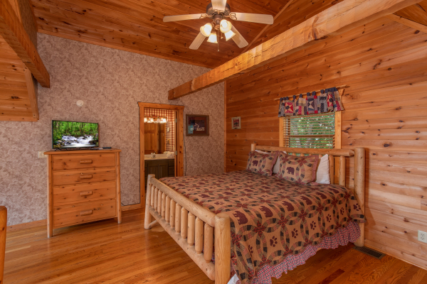 King-sized log bed with a dresser television in a vaulted ceiling bedroom at Cabin in the Clouds, a 3-bedroom cabin rental located in Pigeon Forge